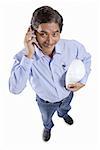 Mature man holding construction hat, using mobile phone, looking at camera