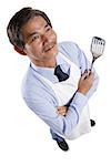 Mature man wearing apron, holding spatula