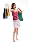 Woman standing, carrying shopping bags in both hands, looking away