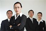 Group of businesspeople, businesswoman in the foreground with arms crossed