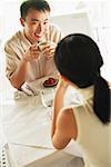 Couple at cafe, man holding coffee cup, facing woman