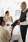 Couple in restaurant, man handing menu back to waiter