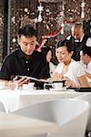 Couple in restaurant, looking through menu, people in the background