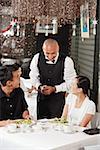 Waiter talking to couple at restaurant