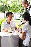 Couple in restaurant, waiter standing next to their table with bill