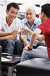 Three guys at a cafe, toasting with drinks