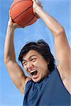 Man holding basketball up, shouting