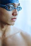 Man in swimming cap and goggles, looking away, portrait