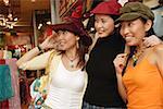 Women shopping, trying on hats, looking away