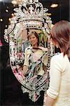 Woman in clothing store, holding dress, looking at mirror