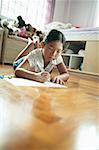 Girl in bedroom, lying on floor, writing on paper