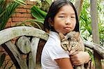 Girl holding cat, looking at camera