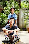 Father sitting on floor, son behind him, looking at camera