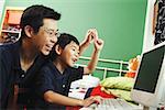 Father and son looking at computer, raising hands