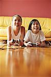 Two sisters lying on floor playing video games