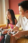 Father and daughter playing video games, father looking at daughter