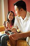 Father and daughter looking at each other, holding video game controllers