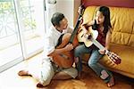 Father and daughter with guitars in living room