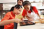 Mother and two daughters in kitchen, baking