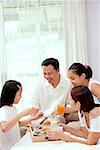 Family of four in bedroom, having breakfast in bed