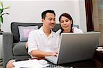 Couple in living room, using laptop