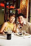 Couple having dinner in Chinese restaurant, smiling at camera