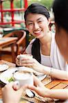 Women eating out, holding cups of coffee