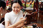 Women sitting in cafe, one holding mobile phone