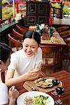 Two women in restaurant, one holding mobile phone