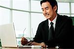 Businessman in office looking at laptop, smiling