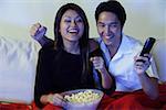 Couple watching TV, making fists, smiling