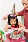 Père et fille en face de la fille tenant le couteau à gâteau, gâteau d'anniversaire