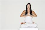 Woman practicing yoga, sitting in lotus position, hands together