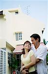 Couple standing in front of house embracing