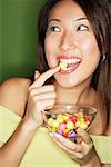 Femme avec un bol de bonbons, mettre des bonbons dans la bouche
