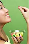 Woman holding single piece of candy and candy bowl