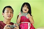 Father and daughter, side by side playing video games