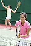 Two women playing tennis, mixed doubles