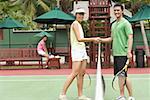 Man and woman shaking hands, looking at camera, tennis match