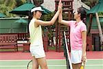 Two women giving high five across tennis net