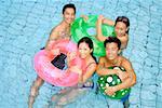 Couples in swimming pool with floats