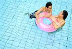 Couple in swimming pool leaning on inflatable ring