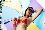 Woman in bikini and sunglasses, holding umbrella