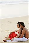 Couple sitting on beach, looking at sea