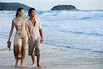 Couple walking on beach, looking away