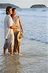 Couple debout sur la plage, l'eau dans la cheville