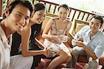 Young adults sitting, having coffee, looking at camera