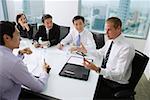 Executives having a discussion around conference table, Caucasian man at the head of the table