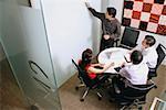 Executives in meeting room, one writing on whiteboard