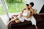 Couple sitting on daybed next to window, embracing